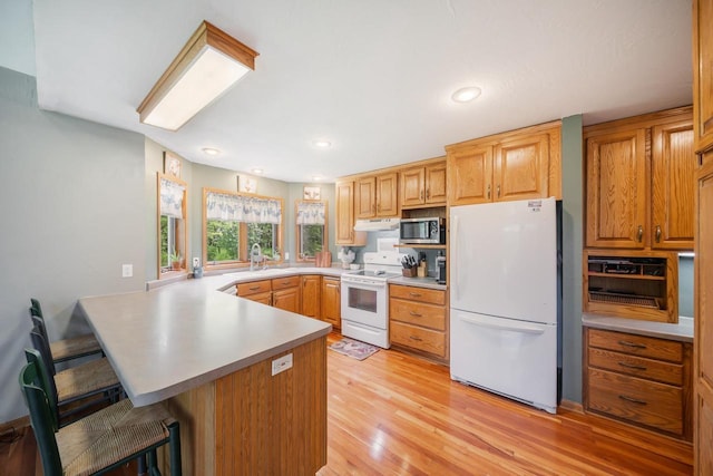 7459 Jensen Rd, Oshkosh, WI 54904 - kitchen with white appliances, a peninsula, a breakfast bar, light wood finished floors, and light countertops