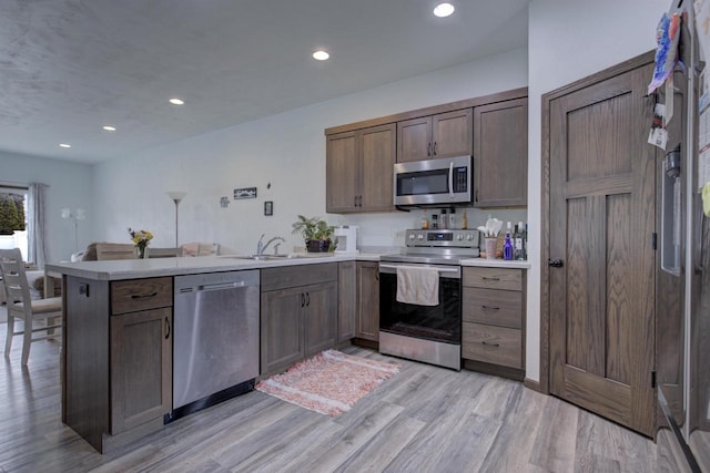 N406 Marion Ave, Appleton, WI 54915 - kitchen with appliances with stainless steel finishes, a peninsula, a sink, light wood-type flooring, and light countertops