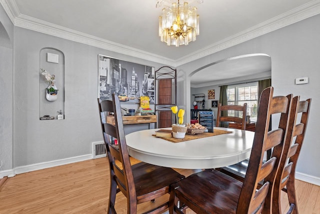 4131 N 41st St, Milwaukee, WI 53216 - dining area featuring arched walkways, baseboards, light wood-type flooring, ornamental molding, and a chandelier