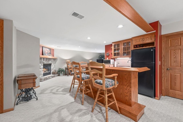 1420 Hidden Fields Dr, West Bend, WI 53095 - kitchen featuring freestanding refrigerator, light colored carpet, stainless steel microwave, a kitchen breakfast bar, and glass insert cabinets