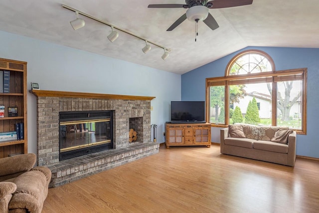 1074 Pendleton Rd, Neenah, WI 54956 - living room with rail lighting, wood finished floors, a fireplace, vaulted ceiling, and ceiling fan
