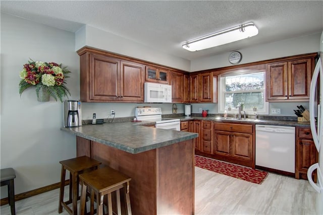 709 E Fillmore Ave, Eau Claire, WI 54701 - kitchen with white appliances, dark countertops, a peninsula, a breakfast bar, and a textured ceiling