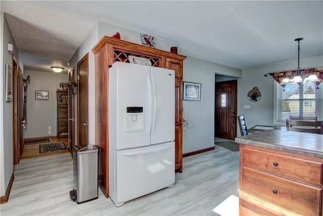 709 E Fillmore Ave, Eau Claire, WI 54701 - kitchen with white fridge with ice dispenser, baseboards, a chandelier, and brown cabinets