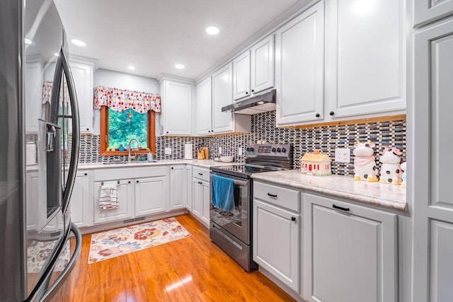 503 N 43rd Ave, Wausau, WI 54401 - kitchen featuring stainless steel appliances, under cabinet range hood, a sink, light wood-style floors, and white cabinetry