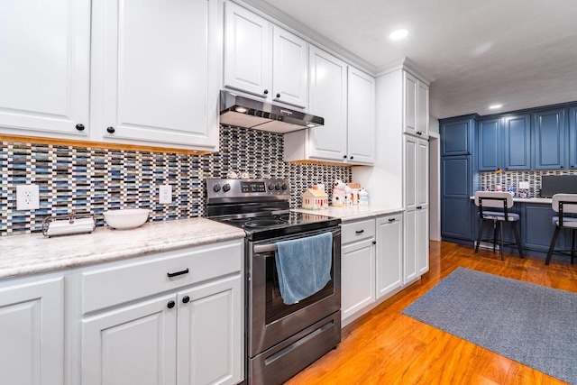 503 N 43rd Ave, Wausau, WI 54401 - kitchen featuring stainless steel electric range oven, under cabinet range hood, decorative backsplash, light countertops, and white cabinetry