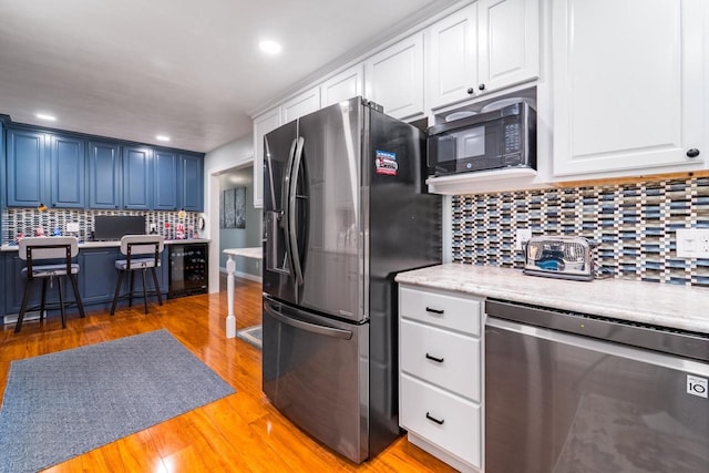 503 N 43rd Ave, Wausau, WI 54401 - kitchen with stainless steel appliances, light countertops, decorative backsplash, light wood finished floors, and white cabinets