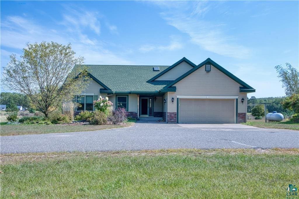 9018 N Anderson Rd, Hayward, WI 54843 - view of front facade featuring concrete driveway, an attached garage, a shingled roof, and a front lawn