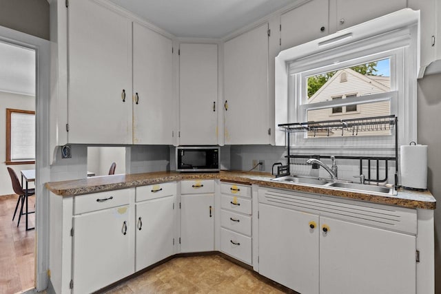 768 Reed St, Neenah, WI 54956 - kitchen with a sink, stainless steel microwave, white cabinets, backsplash, and light flooring