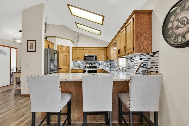 6905 Jamestown Ct, West Bend, WI 53090 - kitchen with stainless steel appliances, a peninsula, decorative backsplash, lofted ceiling, and a sink