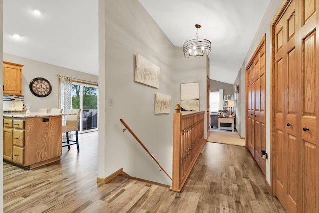 6905 Jamestown Ct, West Bend, WI 53090 - corridor with light wood-type flooring, an upstairs landing, lofted ceiling, a chandelier, and baseboards