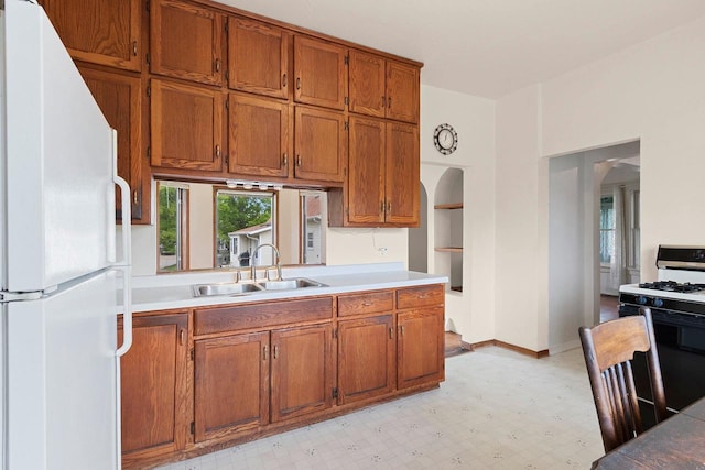 314 Summit St, Pulaski, WI 54162 - kitchen featuring freestanding refrigerator, gas range, brown cabinetry, a sink, and light countertops