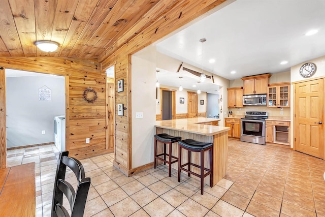 127 Flora St, Pulaski, WI 54162 - kitchen featuring stainless steel appliances, wood walls, light tile patterned floors, recessed lighting, and a breakfast bar
