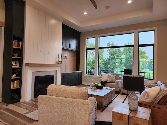 1102 Moll Dr, Waunakee, WI 53597 - living area with a tile fireplace, light wood-type flooring, plenty of natural light, recessed lighting, and a tray ceiling