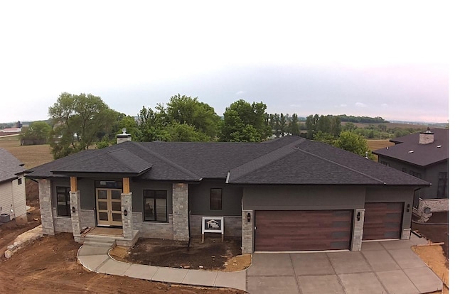 1102 Moll Dr, Waunakee, WI 53597 - view of front facade featuring roof with shingles, stone siding, concrete driveway, a garage, and a chimney