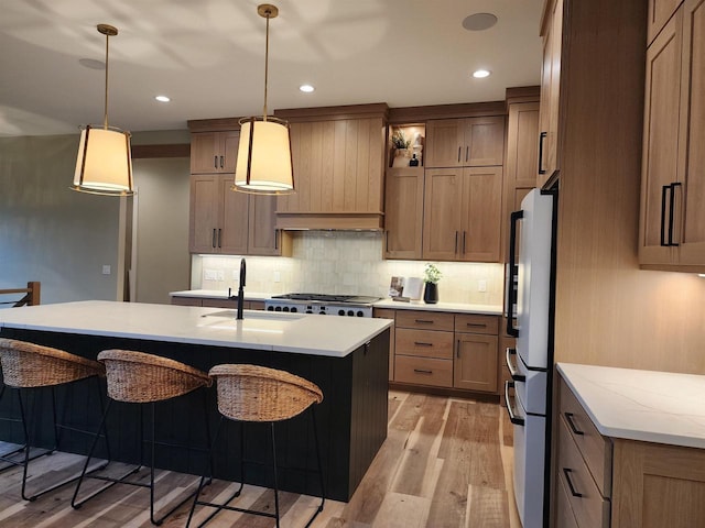 1102 Moll Dr, Waunakee, WI 53597 - kitchen with freestanding refrigerator, a breakfast bar, decorative backsplash, light wood finished floors, and hanging light fixtures