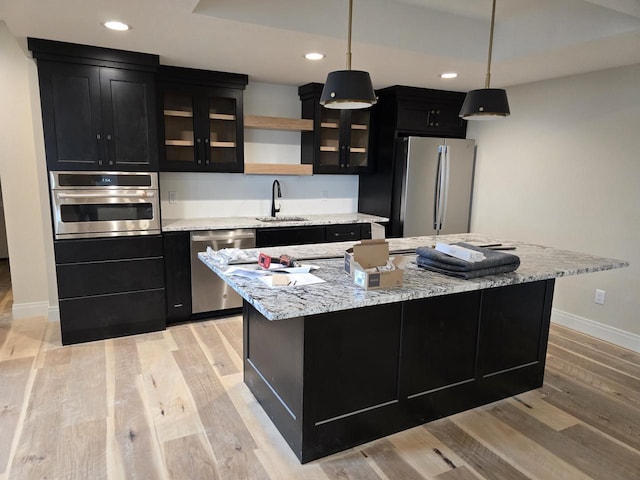 1102 Moll Dr, Waunakee, WI 53597 - kitchen with stainless steel appliances, dark cabinetry, a sink, baseboards, and a kitchen island with sink