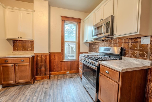 1401 N 2nd St, Wausau, WI 54403 - kitchen with stainless steel appliances, light wood finished floors, wainscoting, light countertops, and white cabinetry