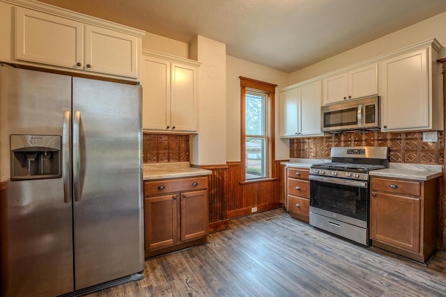1401 N 2nd St, Wausau, WI 54403 - kitchen featuring appliances with stainless steel finishes, dark wood-style flooring, light countertops, a wainscoted wall, and decorative backsplash