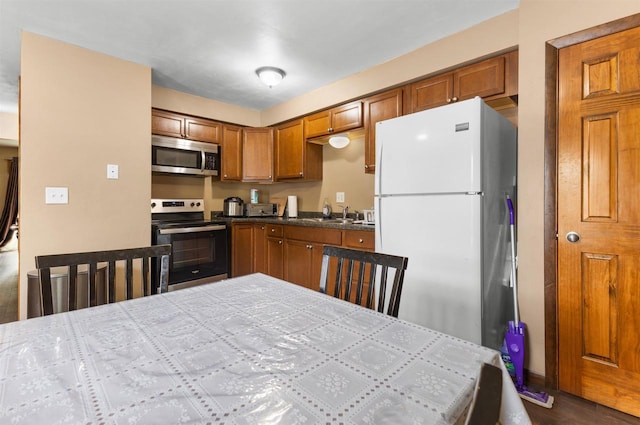 1208 Grove St, Menasha, WI 54952 - kitchen with appliances with stainless steel finishes, brown cabinets, a sink, and dark countertops