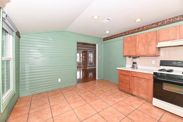 2811 Alpine Ln, Delavan, WI 53115 - kitchen featuring gas stove, under cabinet range hood, lofted ceiling, light countertops, and light tile patterned floors