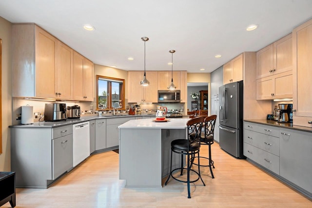 1346 Partridge Ct, Oshkosh, WI 54904 - kitchen with appliances with stainless steel finishes, a kitchen breakfast bar, light wood-type flooring, a center island, and light brown cabinets