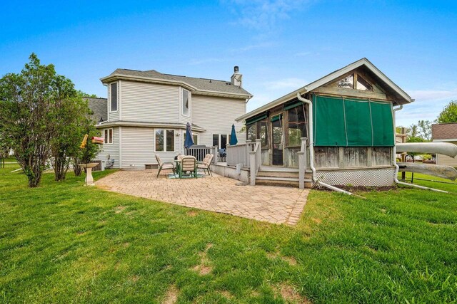 1346 Partridge Ct, Oshkosh, WI 54904 - back of house with a sunroom, a chimney, a patio, and a lawn