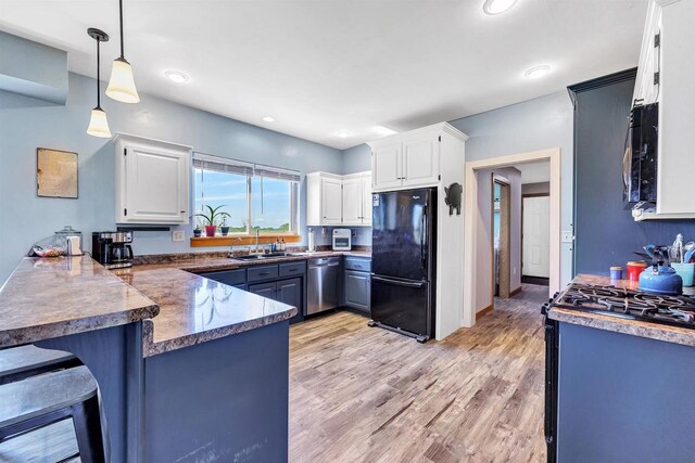 4600 Kamper Ln, Denmark, WI 54208 - kitchen featuring black appliances, a peninsula, white cabinetry, a kitchen breakfast bar, and a sink