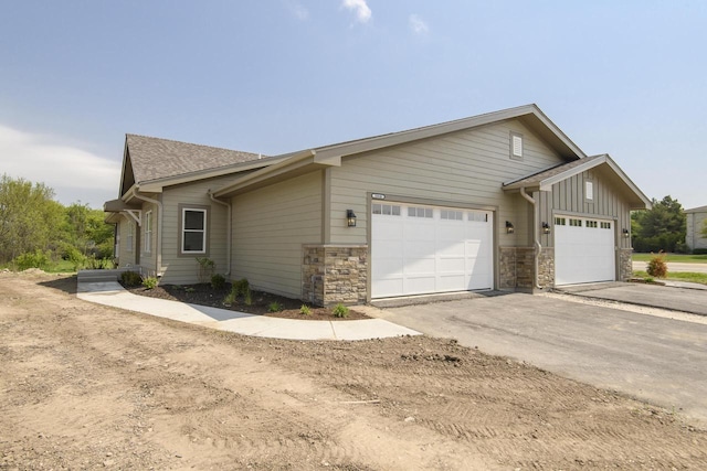 20840 Gray St, Lannon, WI 53046 - view of home's exterior featuring a garage, asphalt driveway, stone siding, and board and batten siding