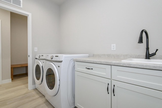 20840 Gray St, Lannon, WI 53046 - laundry area featuring separate washer and dryer, light wood-type flooring, and cabinet space