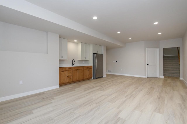 20840 Gray St, Lannon, WI 53046 - unfurnished living room with baseboards, light wood-type flooring, recessed lighting, stairs, and a sink