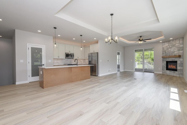 20840 Gray St, Lannon, WI 53046 - kitchen featuring appliances with stainless steel finishes, open floor plan, a raised ceiling, light countertops, and a fireplace