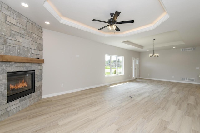 20840 Gray St, Lannon, WI 53046 - unfurnished living room featuring a tray ceiling, a stone fireplace, recessed lighting, a ceiling fan, and a chandelier