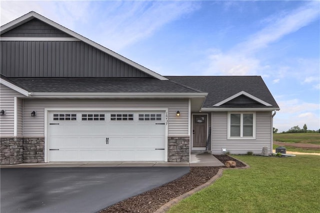 16437 56th Ave, Chippewa Falls, WI 54729 - view of front of property featuring stone siding, a front lawn, asphalt driveway, board and batten siding, and a shingled roof