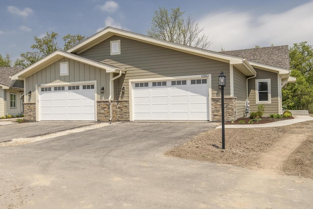 20880 Gray St, Lannon, WI 53046 - view of front of house with stone siding, board and batten siding, asphalt driveway, and an attached garage
