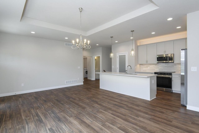 20880 Gray St, Lannon, WI 53046 - kitchen with appliances with stainless steel finishes, a raised ceiling, recessed lighting, tasteful backsplash, and open floor plan