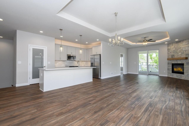 20880 Gray St, Lannon, WI 53046 - kitchen featuring appliances with stainless steel finishes, open floor plan, a raised ceiling, light countertops, and dark wood finished floors