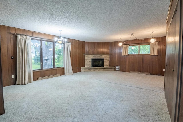 305 N 1st St, Colby, WI 54421 - unfurnished living room with wood walls, carpet flooring, a textured ceiling, a chandelier, and a fireplace