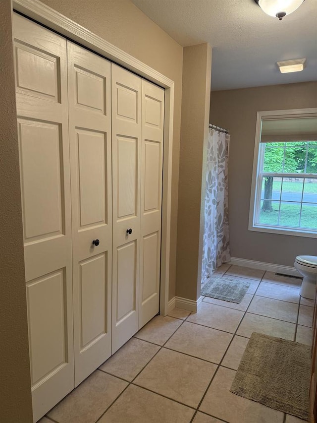 121 Doc Mac Dr, Boscobel, WI 53805 - bathroom featuring toilet, tile patterned flooring, baseboards, a shower with curtain, and a closet