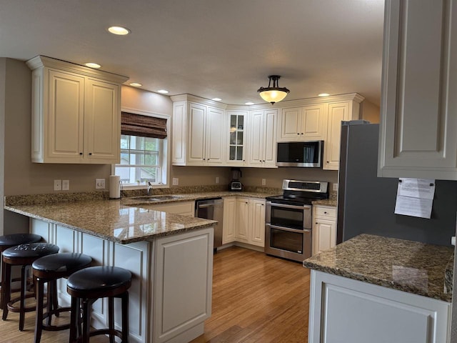 121 Doc Mac Dr, Boscobel, WI 53805 - kitchen featuring appliances with stainless steel finishes, a peninsula, a sink, light wood-type flooring, and a breakfast bar area