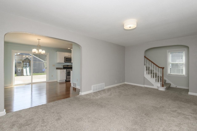 3552 S Pine Ave, Milwaukee, WI 53207 - unfurnished living room with carpet flooring, arched walkways, a chandelier, and stairway