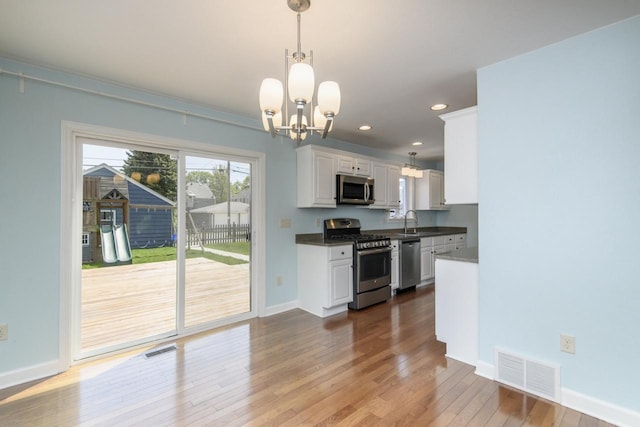 3552 S Pine Ave, Milwaukee, WI 53207 - kitchen featuring appliances with stainless steel finishes, a sink, white cabinets, hardwood / wood-style flooring, and a chandelier