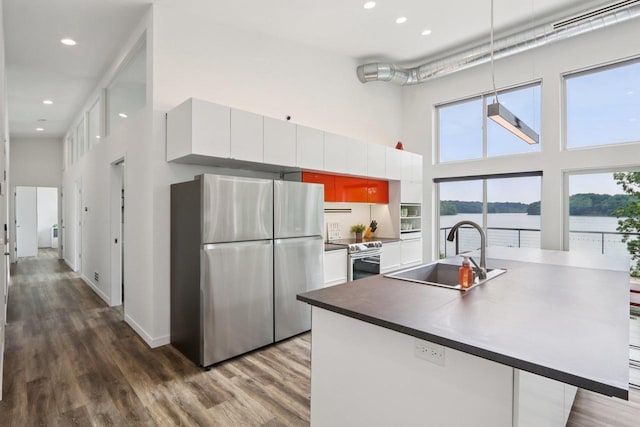 303 Craig Rd, Edgerton, WI 53534 - kitchen featuring appliances with stainless steel finishes, a high ceiling, white cabinetry, dark wood-style floors, and plenty of natural light
