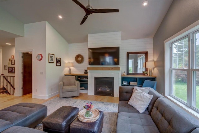 5508 Midmoor Rd, Monona, WI 53716 - living room featuring lofted ceiling, a ceiling fan, light wood finished floors, a glass covered fireplace, and baseboards