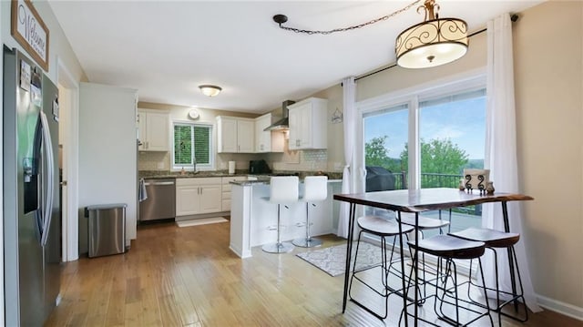1604 Lake Rd, Altoona, WI 54720 - kitchen featuring appliances with stainless steel finishes, wall chimney exhaust hood, backsplash, and light wood-style flooring