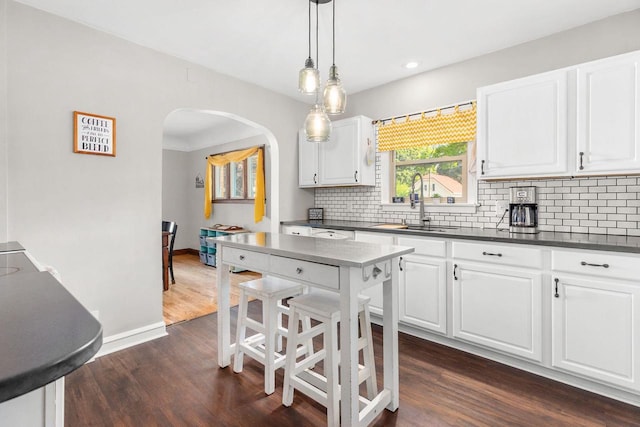813 W Summer St, Appleton, WI 54914 - kitchen with dark countertops, arched walkways, tasteful backsplash, dark wood-type flooring, and baseboards