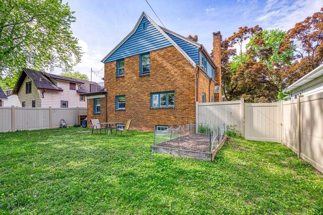 813 W Summer St, Appleton, WI 54914 - rear view of house with a vegetable garden, brick siding, and a chimney