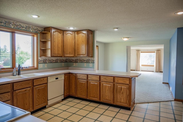 706 Tremont St, Mauston, WI 53948 - kitchen with dishwasher, a sink, brown cabinetry, a peninsula, and light countertops