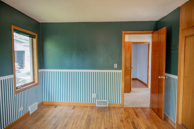 706 Tremont St, Mauston, WI 53948 - unfurnished room featuring hardwood / wood-style floors, plenty of natural light, and wainscoting
