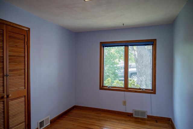 706 Tremont St, Mauston, WI 53948 - unfurnished bedroom featuring multiple windows, baseboards, and wood finished floors