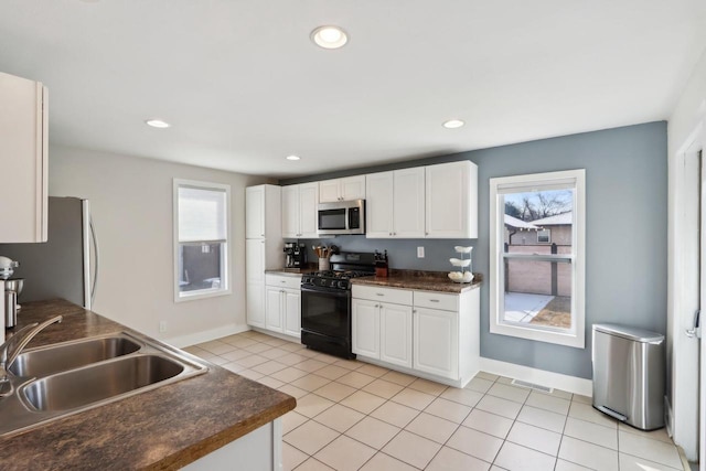 707 E Roland St, Oconomowoc, WI 53066 - kitchen featuring appliances with stainless steel finishes, dark countertops, white cabinetry, a sink, and baseboards